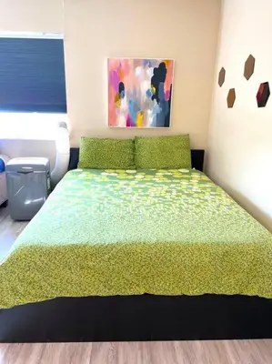 a bedroom with a bed with a green comforter at Right In The Heart Of Pacific Beach in San Diego