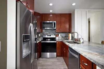 a kitchen with stainless steel appliances and wooden cabinets at Oceanside Beach Condos in Oceanside