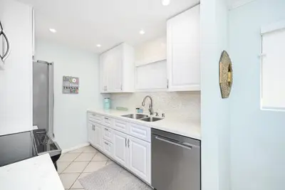 a kitchen with white cabinets and a sink at 2 Bedroom Oceanfront with Patio on the Boardwalk in Newport Beach