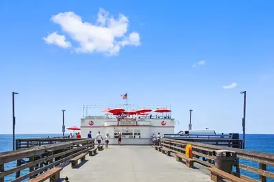 a boat with red umbrellas on a pier at 2 Bedroom Oceanfront with Patio on the Boardwalk in Newport Beach