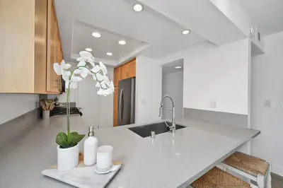 a kitchen counter with a sink and a vase with flowers at NEW - 3 Bedroom near the Balboa Pier and Fun Zone with AC in Newport Beach