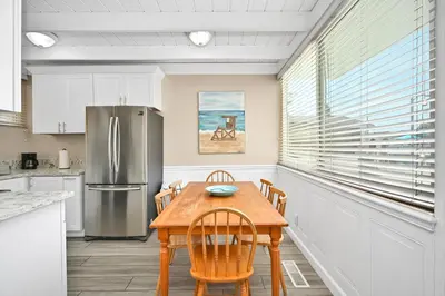 a kitchen with a wooden table and a refrigerator at 5 Bedroom 4 Bath Duplex with Parking on 46th St! in Newport Beach