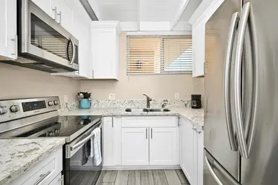 a kitchen with white cabinets and a stainless steel refrigerator at 2 Bedroom Upstairs Apt 1 block from the beach! in Newport Beach