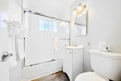a white bathroom with a toilet and a shower at Duplex Across the Street from Beach & Boardwalk in Newport Beach