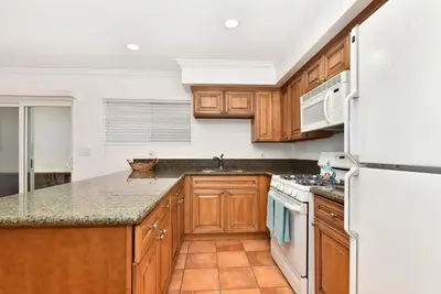 a kitchen with wooden cabinets and a white refrigerator at Oceanfront Triplex on Boardwalk with Ocean Views and Patio in Newport Beach