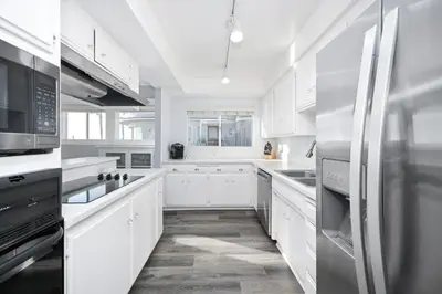 a white kitchen with white cabinets and a refrigerator at Charming 2 Story and 4 Bedroom Home on the Boardwalk in Newport Beach