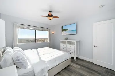 a white bedroom with a bed and a window at Charming 2 Story and 4 Bedroom Home on the Boardwalk in Newport Beach