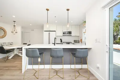 a kitchen with a large island with blue chairs at 3 Bedroom Renovated Condo on Balboa Island in Newport Beach