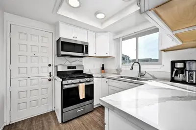 a white kitchen with a stove and a microwave at Charming 1-Bedroom Home on 29th Street in Newport Beach