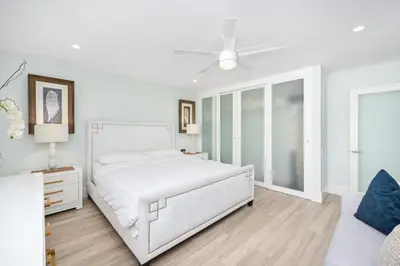 a white bedroom with a bed and a ceiling fan at 5 Bedroom duplex with Patio & Balcony walk to Pier in Newport Beach