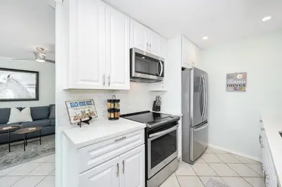 a kitchen with white cabinets and stainless steel appliances at 5 Bedroom duplex with Patio & Balcony walk to Pier in Newport Beach
