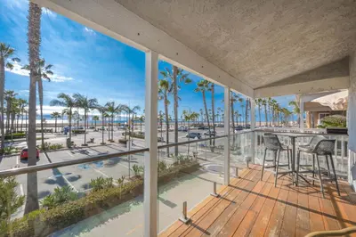 a balcony with a view of the beach and palm trees at 5 Bedroom duplex with Patio & Balcony walk to Pier in Newport Beach