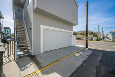 a building with a white garage door and stairs at Remodeled Beach Home with 2 Car Parking Patio and Firepit in Newport Beach