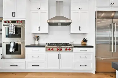a kitchen with white cabinets and a stove top oven at 5 Bedroom Luxury Duplex across from the Beach for 11 people in Newport Beach