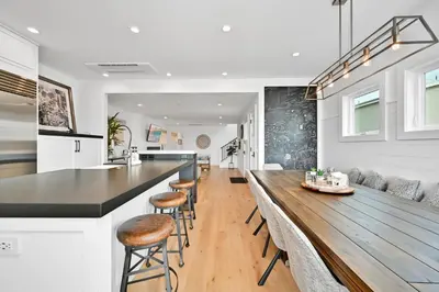 a kitchen and living room with a wooden bar with stools at 5 Bedroom Luxury Duplex across from the Beach for 11 people in Newport Beach