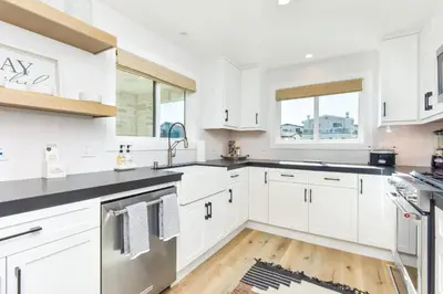 a kitchen with white cabinets and black counter tops at 5 Bedroom Luxury Duplex across from the Beach for 11 people in Newport Beach