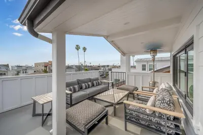 a patio with a couch and chairs on a balcony at 5 Bedroom Luxury Duplex across from the Beach for 11 people in Newport Beach