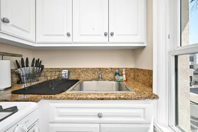 a kitchen counter with a sink and white cabinets at 514 E Oceanfront B in Newport Beach