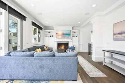 a living room with a blue couch and a fireplace at Upscale Home with Rooftop Deck, Jacuzzi, & Firepit in Newport Beach