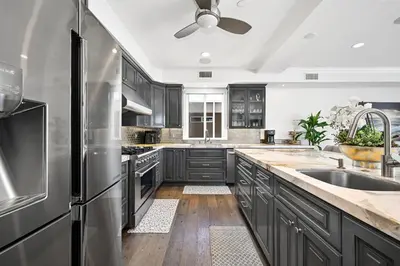 a kitchen with dark wood cabinets and stainless steel appliances at Upscale Home with Rooftop Deck, Jacuzzi, & Firepit in Newport Beach