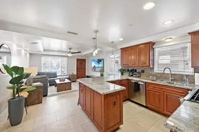 a kitchen with wooden cabinets and a living room at Modern Beach House Steps from the Sand on 39th St in Newport Beach