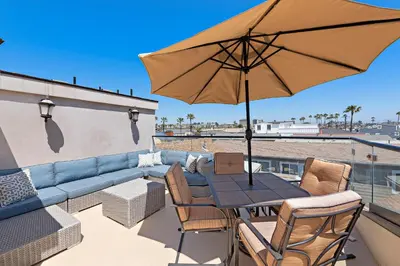 a patio with a table and a couch and an umbrella at Modern Beach House Steps from the Sand on 39th St in Newport Beach