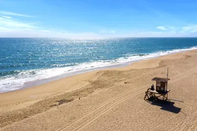 a bench on a beach with the ocean at Modern Beach House Steps from the Sand on 39th St in Newport Beach