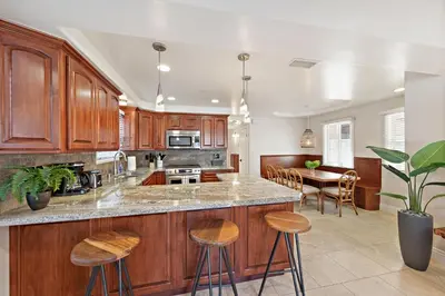 a kitchen with wooden cabinets and a island with bar stools at Modern Beach House Steps from the Sand on 39th St in Newport Beach