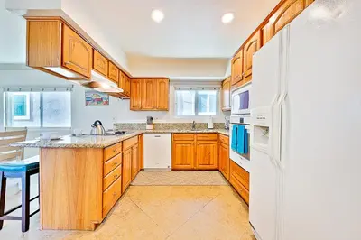 a kitchen with wooden cabinets and a white refrigerator at 2 Story Home with Garage 1 Block to the Beach wi in Newport Beach