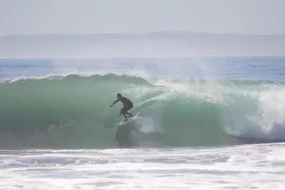 a man riding a wave on a surfboard in the ocean at 2 Story Home with Garage 1 Block to the Beach wi in Newport Beach