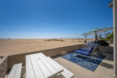 a bench and an umbrella next to the beach at Giant Beachfront Home with Parking near the Pier in Newport Beach