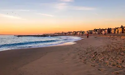 a beach with a person walking on the sand at Newport Beach House in Newport Beach