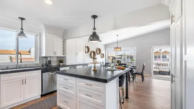 a kitchen with white cabinets and a black counter top at Ocean Breeze Buyout by AvantStay Steps to Beach in Newport Beach