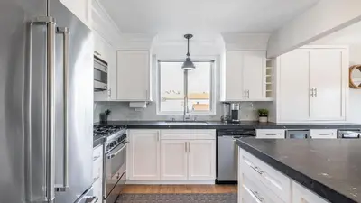 a kitchen with white cabinets and a black counter top at Ocean Breeze Buyout by AvantStay Steps to Beach in Newport Beach