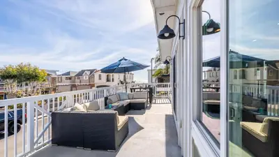 a balcony with chairs and an umbrella at Ocean Breeze Buyout by AvantStay Steps to Beach in Newport Beach
