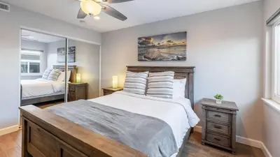 a bedroom with a large bed and a mirror at Ocean Breeze I by AvantStay Steps to the Beach in Newport Beach