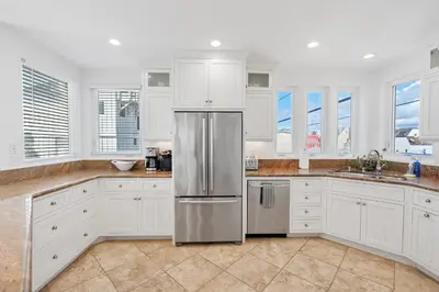 a kitchen with white cabinets and a stainless steel refrigerator at The Mission Beach VIP- 3 Decks, AC, Steps to Sand! in San Diego