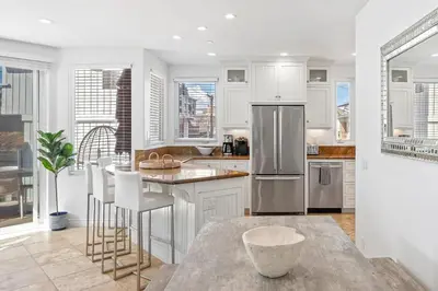 a kitchen with white cabinets and a stainless steel refrigerator at The Mission Beach VIP- 3 Decks, AC, Steps to Sand! in San Diego