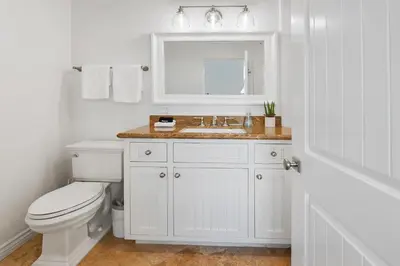 a white bathroom with a toilet and a sink at The Mission Beach VIP- 3 Decks, AC, Steps to Sand! in San Diego