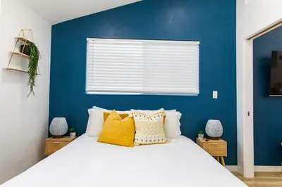 a blue bedroom with a bed with yellow pillows at Stylish Casita min from the beach ! in San Juan Capistrano