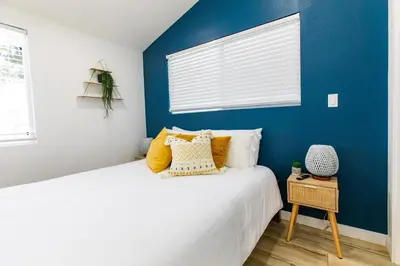 a bedroom with a blue wall and a bed with yellow pillows at Stylish Casita min from the beach ! in San Juan Capistrano