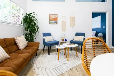 a living room with a brown couch and blue chairs at Stylish Casita min from the beach ! in San Juan Capistrano
