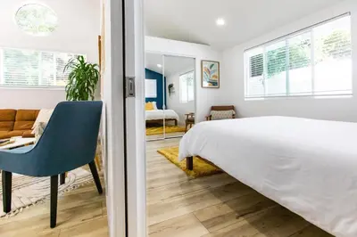a bedroom with a white bed and a blue chair at Stylish Casita min from the beach ! in San Juan Capistrano