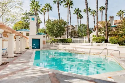 a swimming pool with palm trees and a building at Glamorous Regal Design Home with Private Patio and Garage in Laguna Hills