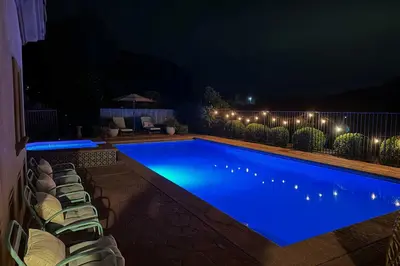 a swimming pool at night with chairs and lights at Escondido Home Private Pool, 2 Grills and Fire Pit! in Escondido
