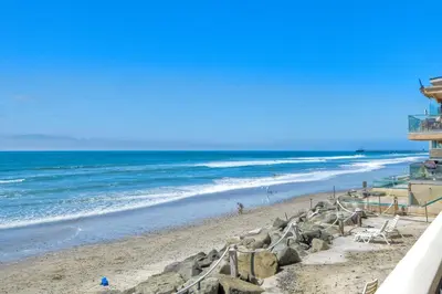a beach with a building and the ocean at Oceanfront 1BR, Fully Furnished, Gated Parking in Oceanside