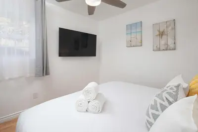a white bedroom with a bed and a tv at 4 Bedroom 2 Bath with Ocean View Hot Tub Parking in San Diego