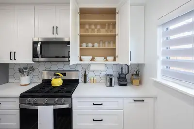 a kitchen with white cabinets and a stove top oven at 2 Bedroom House - Fire Pit Table BBQ - Downtown in San Diego