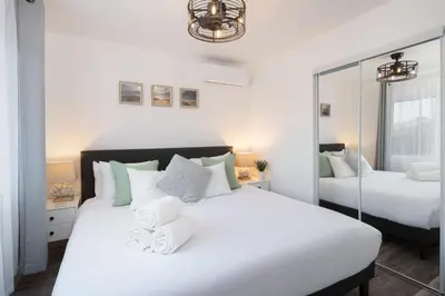 a white bedroom with two beds and a mirror at 3 Bed House with Fire Pit Table and BBQ - Downtown in San Diego