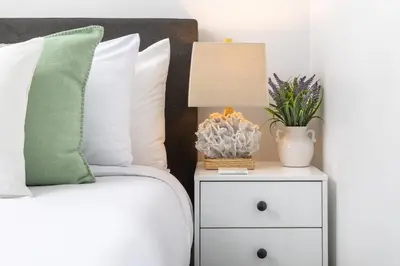 a bed with a nightstand with a lamp and a plant at 3 Bed House with Fire Pit Table and BBQ - Downtown in San Diego